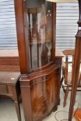 A reproduction Regency bow front corner display with cupboard to base