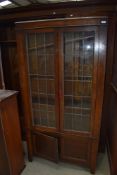 An early 20th Century oak display cabinet having leaded glass doors with cupboard under