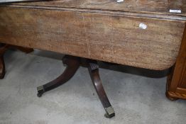 A 19th Century Regency design pedestal table having drop leaf top on turned column and quadruple