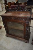 A 19th Century oak side cabinet having carved detailing , frieze drawer and lower glazed cupboard,