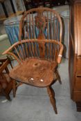 A traditional ash and elm Windsor armchair having crinoline stretcher, some damage to arm