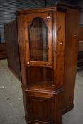 A stained pine corner cabinet having glass door to top.