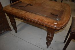 An Edwardian heavy set oak dining table extending with one leaf