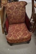 A late 19th or early 20th Century low seat east chair having scroll arms and ball and claw feet