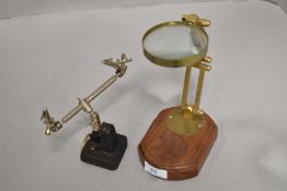 A vintage style brass magnifying glass with wood base and a clamp.