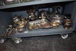A shelf full of vintage and antique flat ware to include tea pots, cutlery, sugar basins and more.