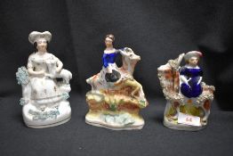 Three Staffordshire flatback figures including ladies sat on goats and a lady with dog on lap