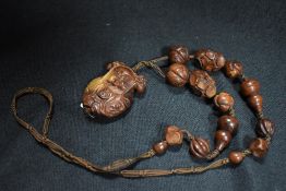 A 20th century Japanese necklace in carved wood with a figure of Geisha girl and hand carved beads