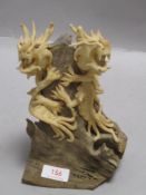 A modern Chinese double dragon figure in ceramic perched on a natural log
