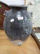 A large glazed earthenware vessel with handles to sides.