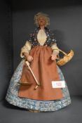 An early 20th century peddler doll having ceramic body with tailored period clothes