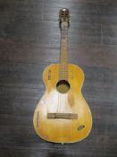 A vintage acoustic guitar, bears various labels including Klira, well loved