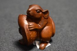 An early 20th century Japanese carved wood Netsuke of a Rat holding a small Carp fish