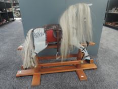 A traditional Rocking Horse in dapple grey having horse hair mane and tail on traditional swing