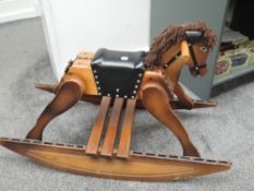 A traditional wooden Rocking Horse having leather seat on rocker base