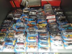 A shelf of modern Mattel Hotwheels diecasts, all on bubble cards, approx 80, some opened