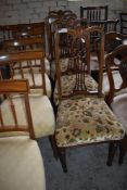 A set of four Edwardian inlaid mahogany dining chairs each with pierced and shaped vase form