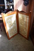 A late Victorian mahogany two fold room screen, with carved and shaped surmounts over embroidered