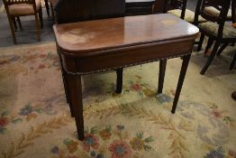An early 20th century mahogany foldover tea table with beaded edge detail and tapering square