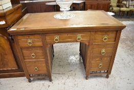 An Edwardian oak kneehole desk, having incised decoration and brass handles. The skiver replaced.
