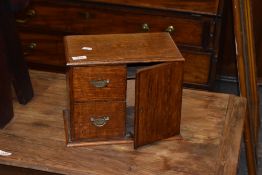 An Edwardian oak smokers cabinet, having single door and two drawers. 24CM. X30CM.