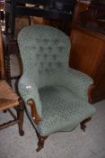 A Victorian stained mahogany deep buttoned spoon back easy chair, having scroll out arms and