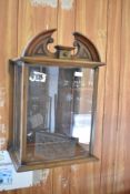 A mahogany 'clock hood' display cabinet, with arched 'broken' pediment over the glazed panels and