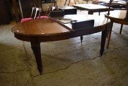 An Edwardian oval mahogany extending dining table, the top with moulded edge detail, raised on