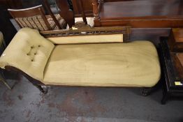A late Victorian mahogany chaise longue, with deep buttoned scrolled arm and spindled back with