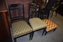 A pair of Victorian ebonised wood bedroom chairs with incised rails and spindled support, sold