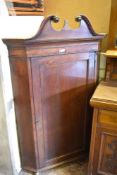 A George III oak corner cupboard with swan neck pediment and single panelled door between canted