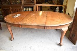 An early 20th century mahogany extending dining table, of circular form with one additional leaf all