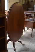 A Victorian mahogany oval loo table with snap top action turned column and for downswept carved