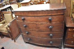 An early 19th century mahogany bow fronted chest of four long cockbeaded drawers, each with turned