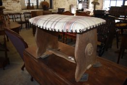 An upholstered oak stool, of trestle form with slightly bowed seat and studded upholstery. 40CM X.