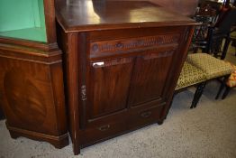 An Edwardian mahogany cupboard, the large door with rosette carved and nulled upper panel over two