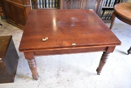 A Victorian mahogany draw-out dining table, having turned legs finishing in brass caps and
