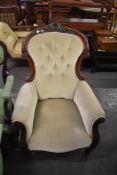 A Victorian mahogany easychair, having a deep button spoon back surmounted with carved cresting over