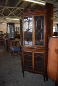 An Edwardian inlaid and astragal glazed double corner cupboard having a fret cut arched pediment
