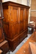 A large modern figured mahogany triple wardrobe of 19th century design with panelled doors over