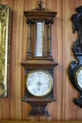 A Victorian carved oak barometer, having an architectural pediment with central urn form finial over