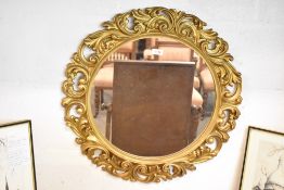 A 20th century circular gilt frame mirror, profusely molded with scrolls. 59CM.