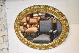 A 20th century ornate oval gilt framed mirror, with bevelled plate. 74CM.