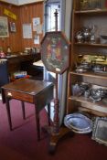 A Victorian mahogany pole screen, the canted rectangular screen with needlework armorial, over a