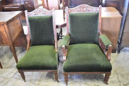 A pair of Victorian carved mahogany his and hers easy chairs, the crest rails carved with central