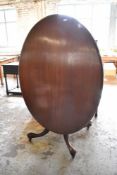 A Victorian mahogany oval snap top loo table, the top raised on four turned and fluted supports