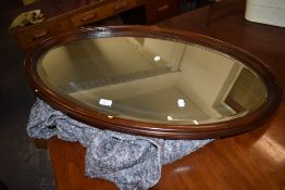A 1920s design mahogany framed oval bevelled wall mirror 94CM.