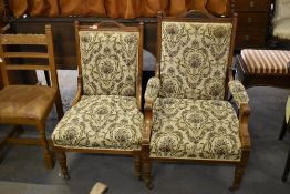 A pair of Victorian oak his and hers easy chairs, with arched and scrolled carved crest rail between