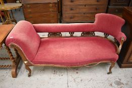 A late Victorian walnut framed chaise longue, with scrolled padded arm, carved and pierced