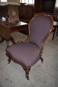 A Victorian mahogany spoon back nursing chair, the padded and scrolled spoon back over a